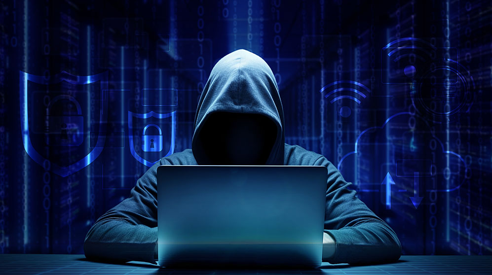 Photo of a hooded hacker on a computer